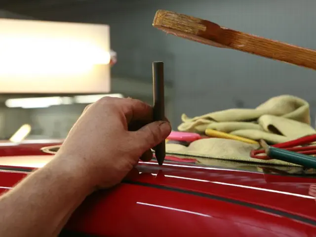 Technician working on a red car body panel
